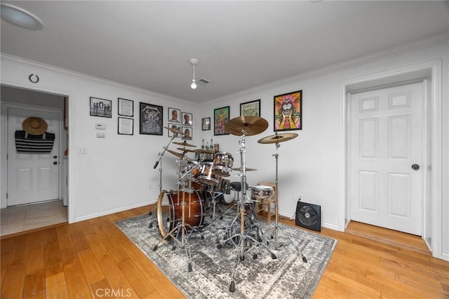 rec room with light wood-style floors, crown molding, and baseboards