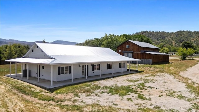 back of house featuring covered porch, a mountain view, and central AC