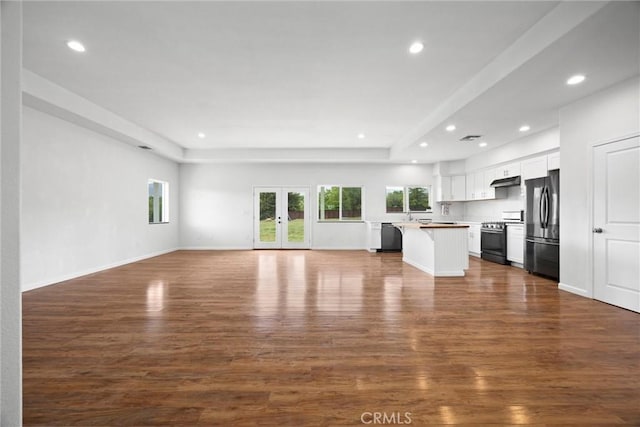 unfurnished living room featuring recessed lighting, dark wood-type flooring, baseboards, and a sink