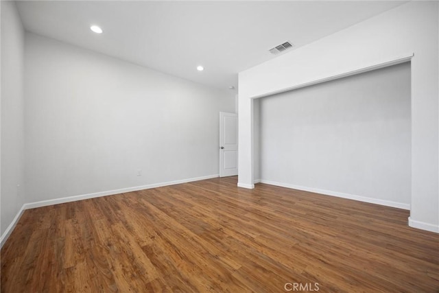 spare room featuring recessed lighting, wood finished floors, and baseboards