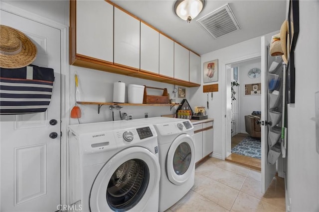clothes washing area featuring cabinet space, washer and dryer, and light tile patterned flooring
