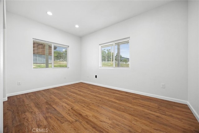 empty room featuring wood finished floors, baseboards, and recessed lighting