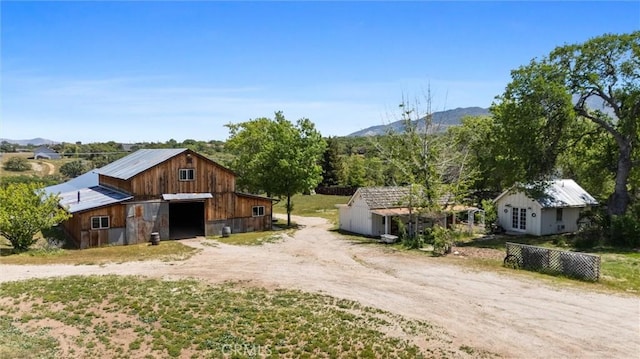 view of front of house with driveway, a barn, a detached garage, and a mountain view