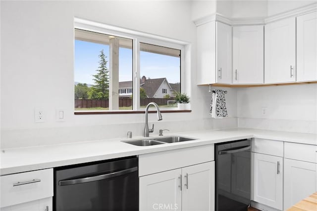 kitchen with stainless steel dishwasher, a sink, white cabinetry, and light countertops
