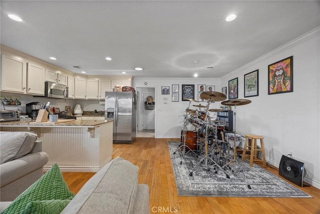 kitchen featuring stainless steel appliances, a peninsula, a kitchen breakfast bar, recessed lighting, and ornamental molding