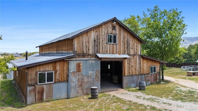 rear view of property featuring a barn, a detached garage, an outdoor structure, and metal roof