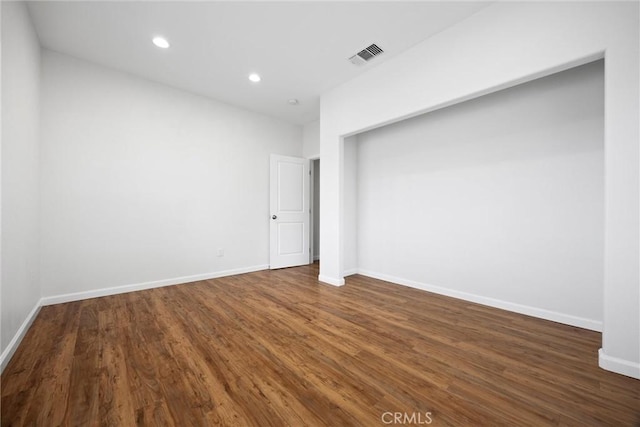 empty room with dark wood finished floors, recessed lighting, and baseboards