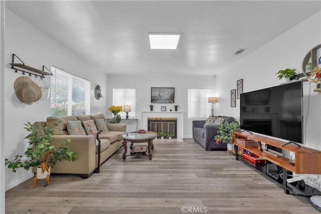 living area with a fireplace, light wood-style flooring, and baseboards