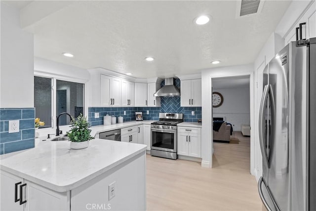 30 Yorktown, Irvine, CA 92620 - kitchen with stainless steel appliances, wall chimney exhaust hood, white cabinetry, a peninsula, and recessed lighting