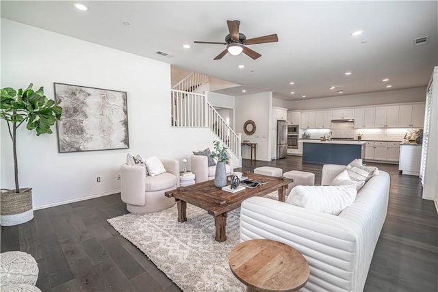 living area featuring stairs, a ceiling fan, recessed lighting, dark wood finished floors, and baseboards