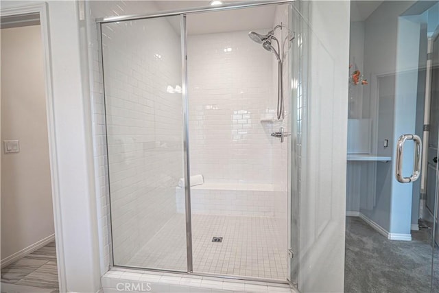 full bathroom with a stall shower and baseboards