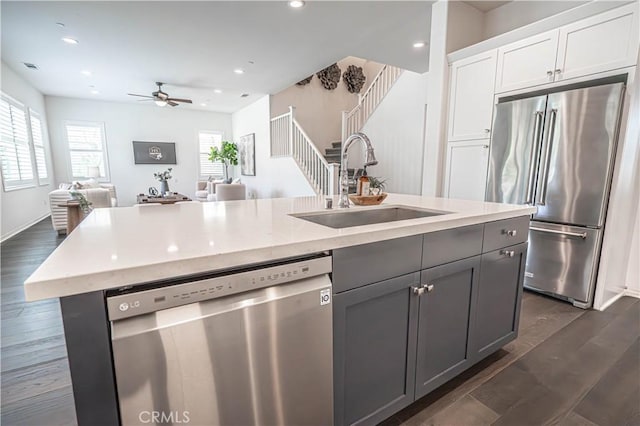 kitchen with stainless steel appliances, a sink, open floor plan, gray cabinets, and white cabinetry