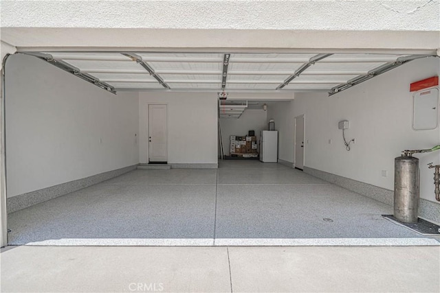 garage featuring freestanding refrigerator and baseboards