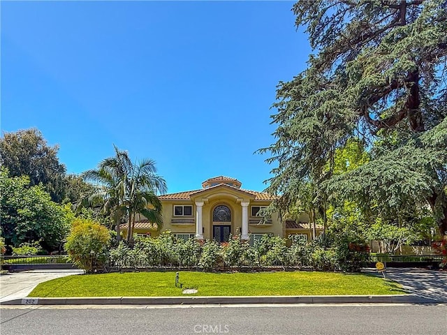 mediterranean / spanish-style house with stucco siding, a tile roof, and a front lawn