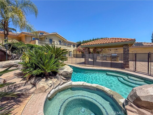 view of swimming pool featuring a pool with connected hot tub and fence