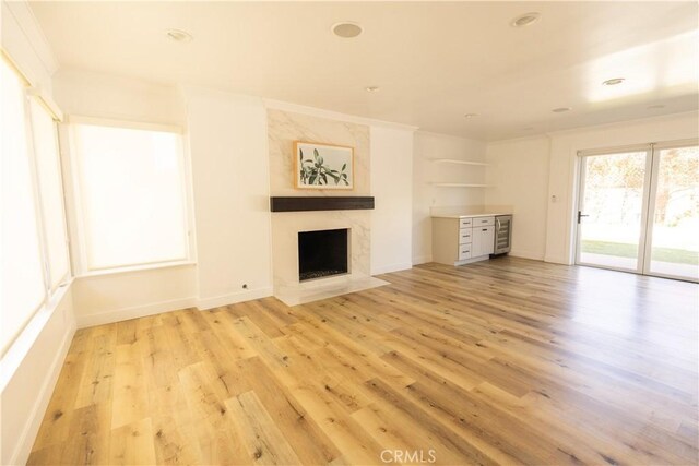 12539 Presnell St, Los Angeles, CA 90066 - unfurnished living room featuring a premium fireplace, light wood-style floors, wine cooler, crown molding, and baseboards