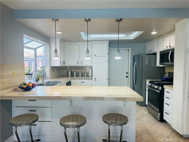 25690 Onate Dr, Moreno Valley, CA 92557 - kitchen featuring stainless steel appliances, a sink, a peninsula, backsplash, and white cabinets