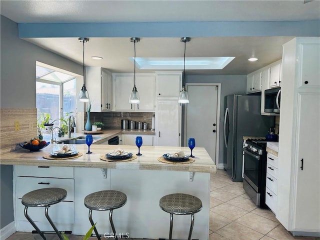 25690 Onate Dr, Moreno Valley, CA 92557 - kitchen featuring appliances with stainless steel finishes, a sink, a peninsula, tasteful backsplash, and light countertops