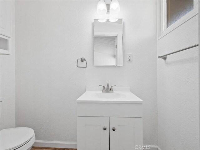 15533 Heartsease Ln, Victorville, CA 92395 - bathroom featuring vanity, toilet, wood finished floors, and baseboards