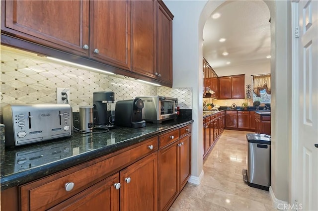 16418 Village Meadow Dr, Riverside, CA 92503 - kitchen with arched walkways, decorative backsplash, dark stone counters, recessed lighting, and light tile patterned flooring