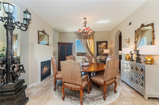 16418 Village Meadow Dr, Riverside, CA 92503 - dining space featuring a chandelier, healthy amount of natural light, arched walkways, and a glass covered fireplace