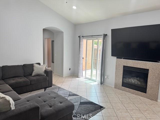 1421 Alta Palma Rd, Perris, CA 92571 - living room featuring light tile patterned floors, arched walkways, a tile fireplace, and high vaulted ceiling