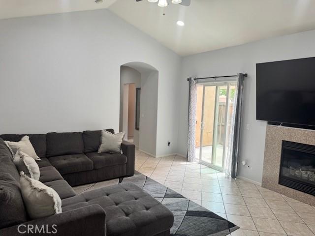 1421 Alta Palma Rd, Perris, CA 92571 - living room featuring light tile patterned floors, arched walkways, a ceiling fan, lofted ceiling, and a tiled fireplace