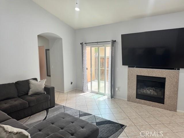 1421 Alta Palma Rd, Perris, CA 92571 - living room with arched walkways, light tile patterned floors, baseboards, a tiled fireplace, and vaulted ceiling