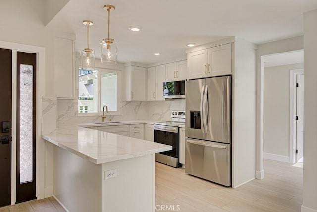 47 Calle Aragon Unit D, Laguna Woods, CA 92637 - kitchen featuring appliances with stainless steel finishes, a sink, a peninsula, backsplash, and white cabinets