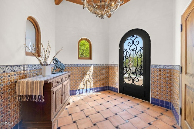 10971 Alto Ct, Oak View, CA 93022 - foyer entrance with wainscoting, a chandelier, tile walls, beam ceiling, and a high ceiling
