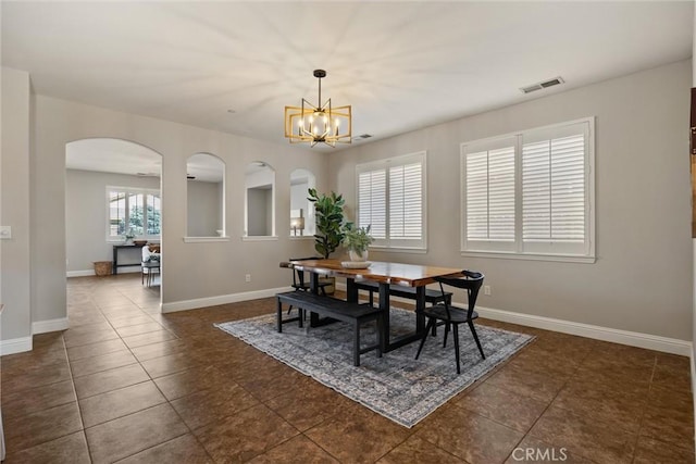 7 Abbott Cir, Chico, CA 95973 - dining space featuring a chandelier, arched walkways, dark tile patterned floors, and baseboards