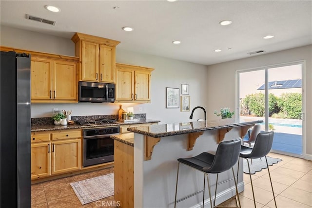 7 Abbott Cir, Chico, CA 95973 - kitchen with appliances with stainless steel finishes, a kitchen breakfast bar, dark stone countertops, light brown cabinets, and light tile patterned floors