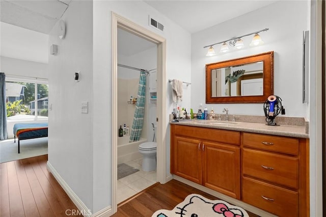 full bath with wood finished floors, vanity, shower / bath combo with shower curtain, toilet, and baseboards