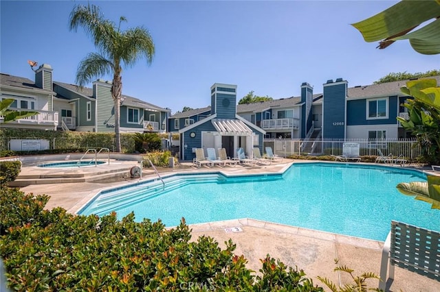community pool with fence, a hot tub, a residential view, and a patio