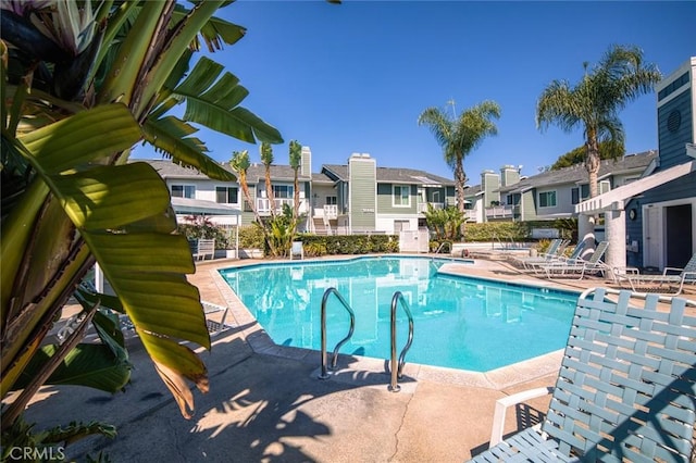 community pool with a residential view and a patio area