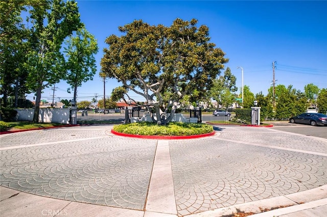 view of road featuring a gate, curbs, and street lighting