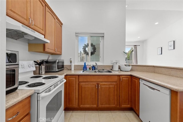 kitchen with white appliances, under cabinet range hood, a sink, light tile patterned floors, and light countertops