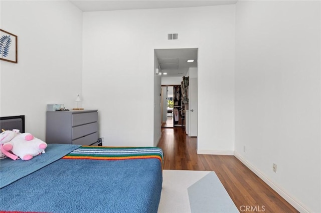 bedroom featuring wood finished floors, baseboards, and attic access