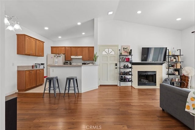 living area featuring vaulted ceiling, wood finished floors, a brick fireplace, and recessed lighting