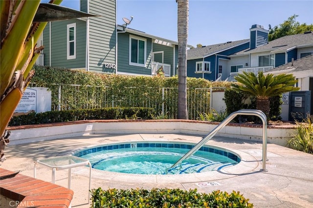 view of swimming pool featuring a community hot tub and fence