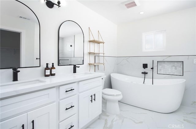 12842 Elizabeth Way, Tustin, CA 92780 - bathroom featuring marble finish floors, a freestanding bath, tile walls, double vanity, and toilet