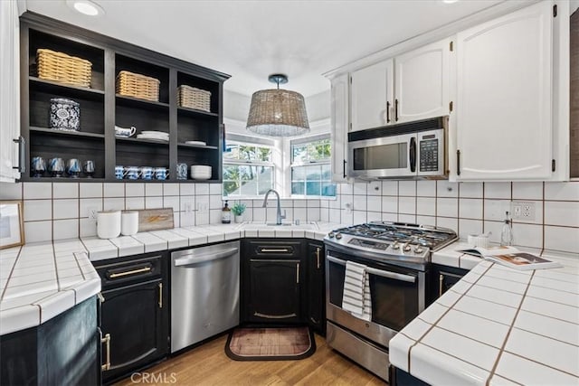 3061 Wood Dr, Cambria, CA 93428 - kitchen with appliances with stainless steel finishes, tile countertops, white cabinetry, and open shelves
