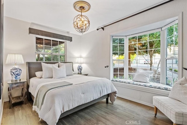 3061 Wood Dr, Cambria, CA 93428 - bedroom featuring a chandelier, multiple windows, wood finished floors, and baseboards