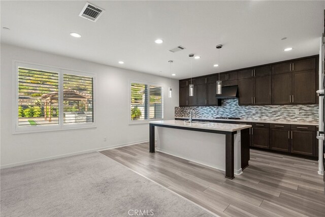 28600 Foothill Way, Saugus, CA 91350 - kitchen with stovetop, light countertops, dark brown cabinets, backsplash, and light wood finished floors