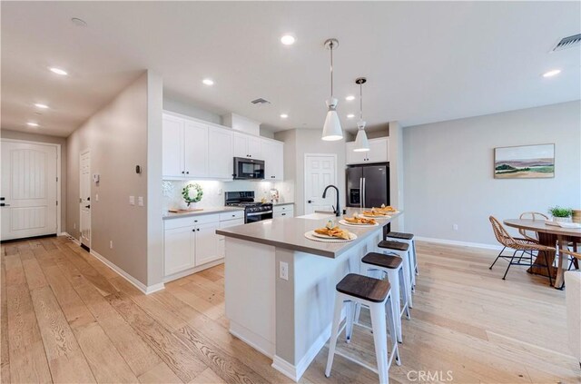 1705 Almond Tree Pl, Upland, CA 91784 - kitchen with stainless steel appliances, light wood finished floors, an island with sink, white cabinets, and recessed lighting