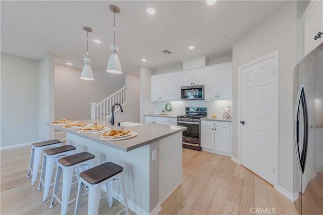 1705 Almond Tree Pl, Upland, CA 91784 - kitchen with stainless steel appliances, a sink, light wood-type flooring, a kitchen bar, and white cabinets