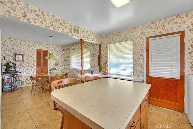 18021 E Cypress St, Covina, CA 91722 - kitchen with wallpapered walls, light tile patterned floors, light countertops, a kitchen island, and decorative light fixtures