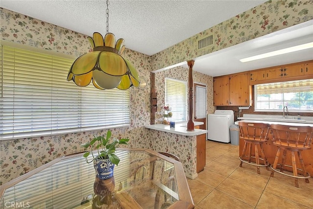 18021 E Cypress St, Covina, CA 91722 - kitchen with washer / dryer, wallpapered walls, a sink, light tile patterned floors, and a textured ceiling