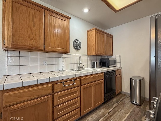 540 Pico Ave Unit 110, San Simeon, CA 93452 - kitchen featuring black appliances, dark wood-type flooring, a sink, tasteful backsplash, and brown cabinetry