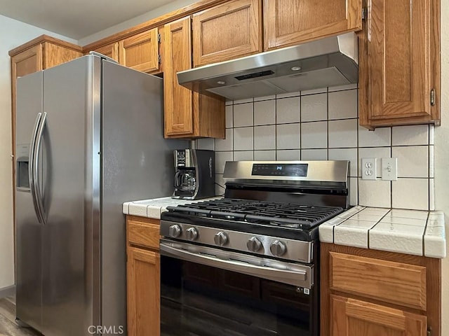 540 Pico Ave Unit 110, San Simeon, CA 93452 - kitchen with stainless steel appliances, under cabinet range hood, tile counters, and decorative backsplash
